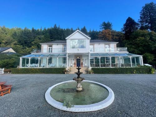 una casa grande con una fuente frente a ella en Plas Maenan en Conwy