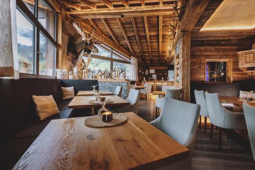 un restaurante con mesas y sillas de madera y ventanas en Margarethenstein Boutique Hotel en Kaprun