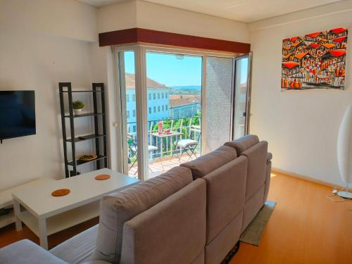 a living room with a couch and a large window at Figueira Family Apartment in Figueira da Foz