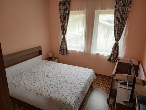 a bedroom with a bed and two windows at Апартамент за гости Виктория in Chepelare