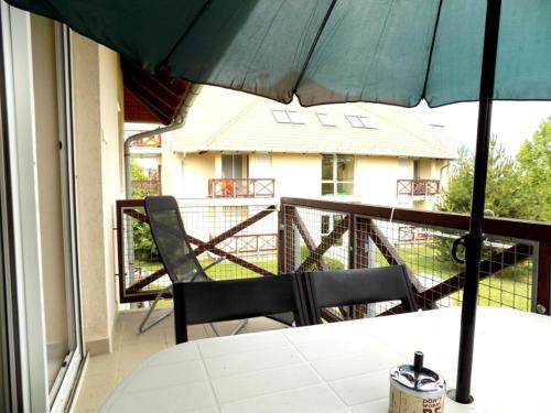 une table et des chaises sur un balcon avec un parasol dans l'établissement 58 - Hullám Üdülőparkban vízközeli modern stúdió apartman, à Balatonőszöd