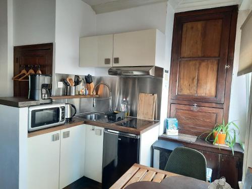 une cuisine avec un évier et un micro-ondes dans l'établissement Studio Le Ras d'Eau à Granville, à Granville