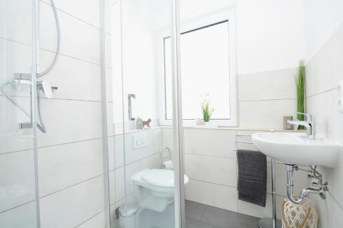 a white bathroom with a toilet and a sink at CO05-HI Apartment in Coburg in Coburg