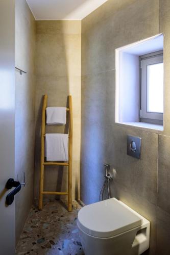 a bathroom with a toilet and a ladder and a window at Vrachos Suites Mykonos in Mýkonos City