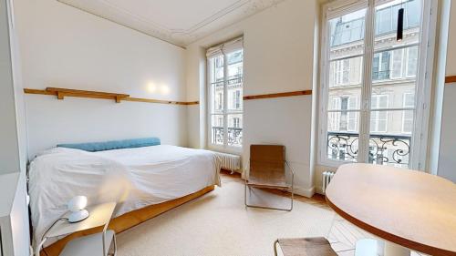 une chambre avec un lit, une table et des fenêtres dans l'établissement JOIVY Premium flats in the heart of the 9th arr, near Moulin Rouge, à Paris