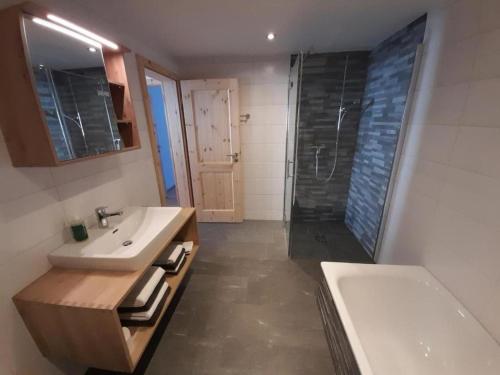 a bathroom with a sink and a shower and a tub at Ferienwohnung im Chalet Adelheid in Grindelwald