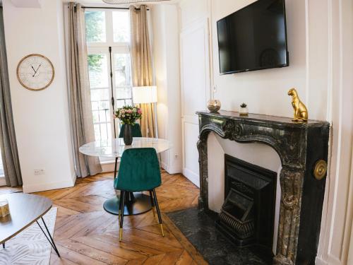 a living room with a fireplace and a green chair at Superbe T2 avec vue sur cour - Rouen centre in Rouen
