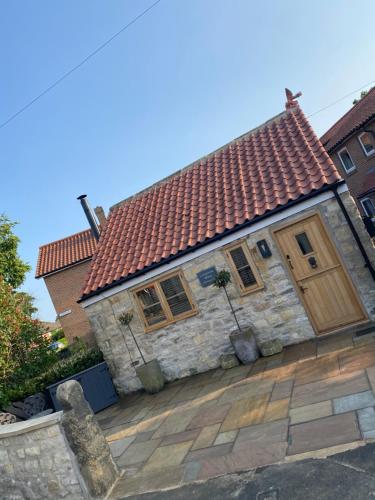 a brick house with a red roof on a patio at Cornerstone House in Pickering