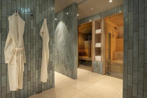 uma casa de banho com paredes em azulejos cinzentos e uma cabina de duche ao nível do chão em Maritim Hotel München em Munique