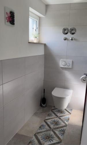 La salle de bains blanche est pourvue de toilettes et d'une fenêtre. dans l'établissement Gemütliches Ferienzimmer in Neukirchen, à Braunfels