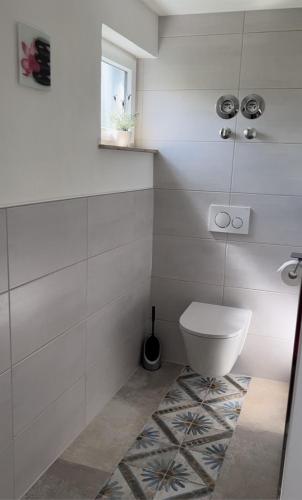 a white bathroom with a toilet and a window at Gemütliches Ferienzimmer in Neukirchen in Braunfels