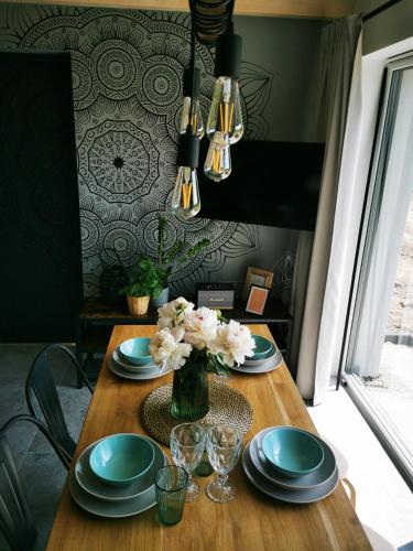 a wooden table with plates and a vase of flowers at Przystań Dobrej Energii, domki całoroczne z gorącą balią z hydromasażem in Kłodzko
