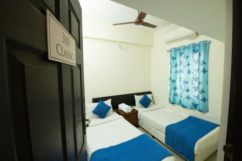 two beds in a small room with a door at High Point Serviced Apartment in Tiruchchirāppalli