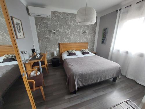 a bedroom with a bed and a table with a desk at Chez Terrassier - Logis Hôtels - Hotel et Restaurant in Vaissac