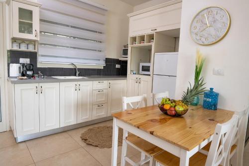 a kitchen with a wooden table and a clock on the wall at סוויטות לוגאסי - דירות אירוח נעימות עם מרפסת פרטית מול הנוף in Sheʼar Yashuv