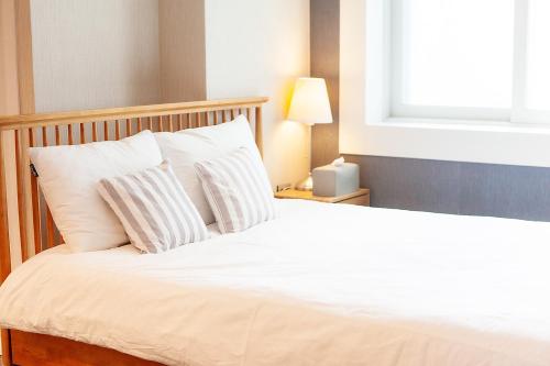 a bed with white sheets and pillows next to a window at Hostel Mihojae Busan in Busan