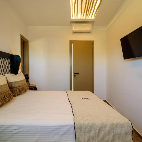 a bedroom with a large white bed and a flat screen tv at Vrachos Suites Mykonos in Mýkonos City