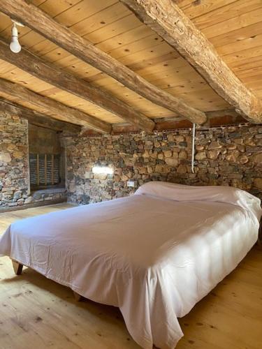 a bedroom with a white bed in a stone wall at EL PALLER in Riudarenes