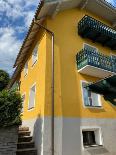 a yellow and white building with a balcony at Ferienwohnung, wenige Minuten vom Wörthersee in Schiefling am See
