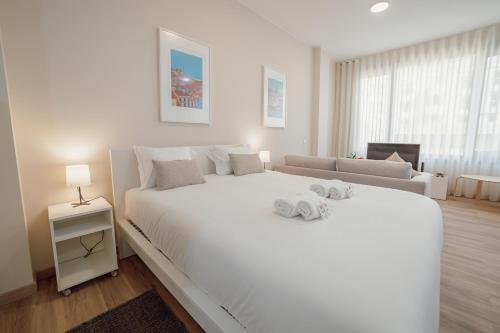 ein weißes Schlafzimmer mit einem großen weißen Bett und einem Sofa in der Unterkunft Modern Trindade by Homing in Porto