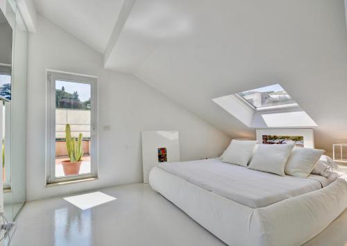ein weißes Schlafzimmer mit einem Bett und einem Fenster in der Unterkunft Penthouse Marina-Seaview Jacuzzi and Terrace in Rapallo