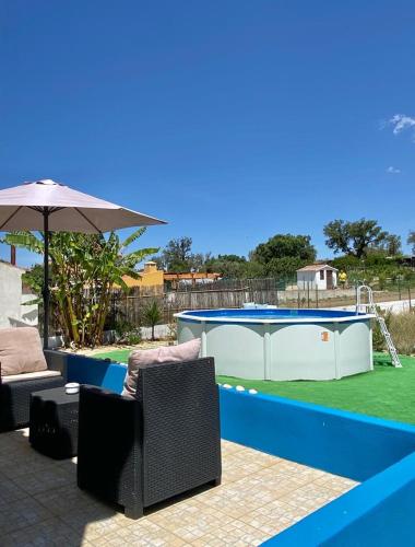 a patio with two chairs and an umbrella next to a pool at Serra mar in Cruz de João Mendes