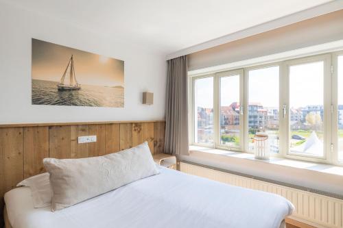 a bedroom with a bed and two windows at West Bay in Middelkerke