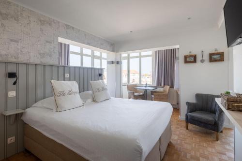 a bedroom with a large white bed and a chair at West Bay in Middelkerke