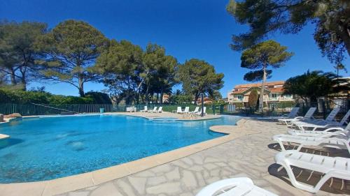 - une piscine avec des chaises longues blanches et un complexe dans l'établissement Méditerranée paradise, à Saint-Raphaël