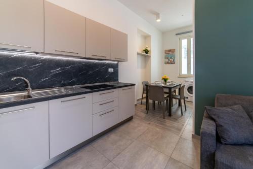 a kitchen with white cabinets and a dining room at Villa Gina Case Vacanze in Roseto degli Abruzzi