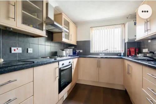 a large kitchen with wooden cabinets and appliances at Home in Medway 3bedroom free sports channel, parking in Chatham