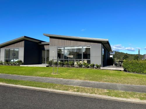 a large house with a grass yard in front of it at Purangi Beachhouse in Cooks Beach