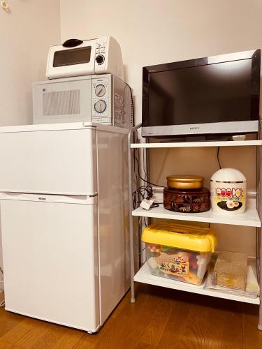 a refrigerator with a microwave and a tv on a shelf at Osaka SENJU2 traditional Tatami whole house 2-5 ppl 3 mins walk to station in Osaka