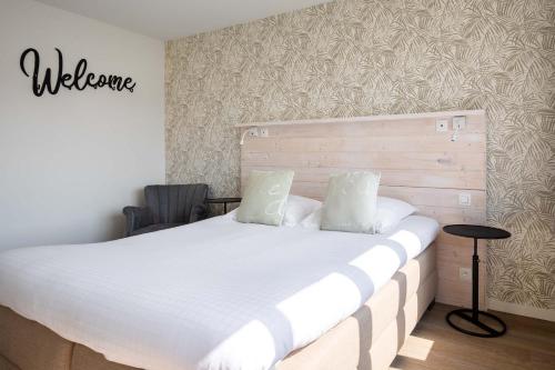 a bedroom with a large white bed with a wooden headboard at West Bay in Middelkerke