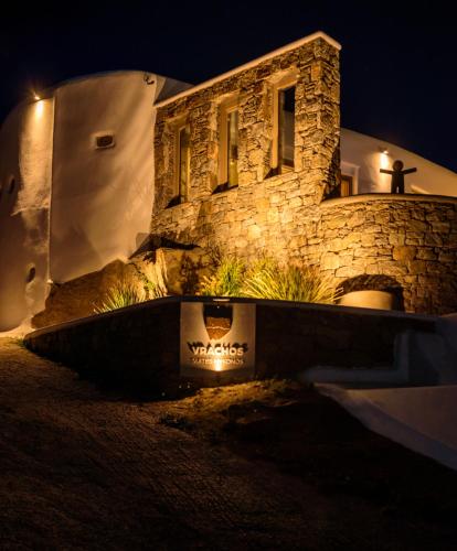 a stone building with a sign in front of it at night at Vrachos Suites Mykonos in Mýkonos City