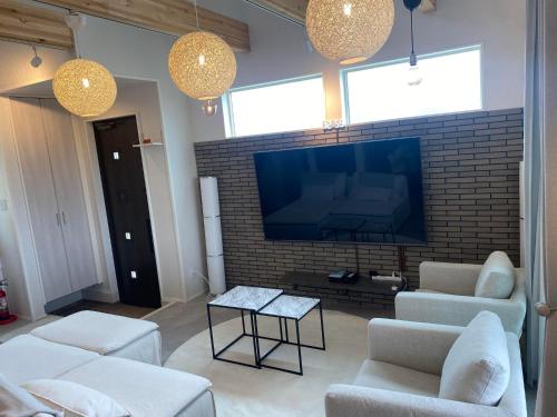 a living room with a tv and a brick wall at きくのこ3缶ヴィラ＆テラス　 in Miyako Island