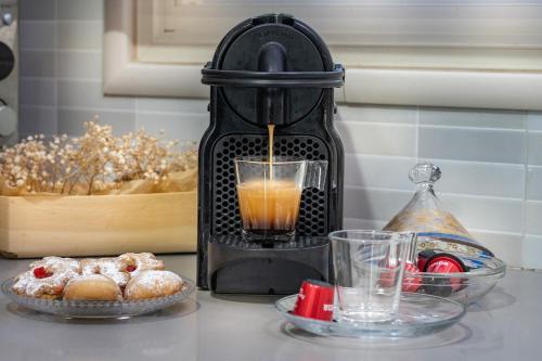 a black coffee maker with a glass of orange juice at סוויטות לוגאסי - דירות אירוח נעימות עם מרפסת פרטית מול הנוף in Sheʼar Yashuv