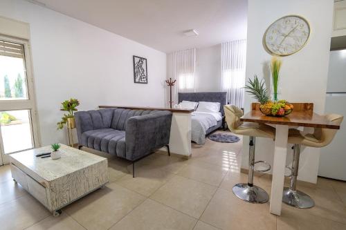 a living room with a couch and a clock on the wall at סוויטות לוגאסי - דירות אירוח נעימות עם מרפסת פרטית מול הנוף in Sheʼar Yashuv