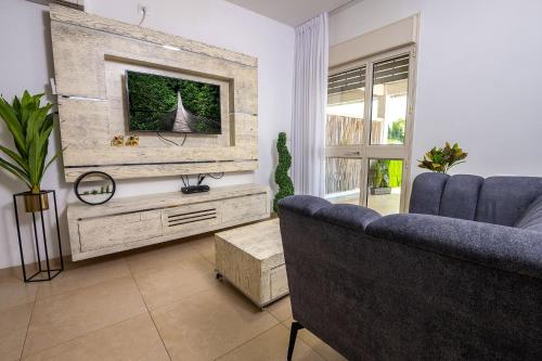 a living room with a couch and a tv at סוויטות לוגאסי - דירות אירוח נעימות עם מרפסת פרטית מול הנוף in Sheʼar Yashuv