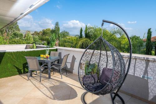 a swing on a balcony with a table and chairs at סוויטות לוגאסי - דירות אירוח נעימות עם מרפסת פרטית מול הנוף in Sheʼar Yashuv