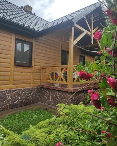 a log cabin with a deck and flowers at Chmielna Chatka in Majdan Łuczycki