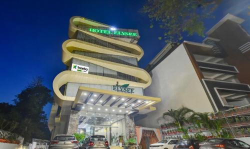d'une tour d'hôtel avec des voitures garées à l'extérieur dans l'établissement Treebo Trend Elysee - Patel Nagar, à Dehradun