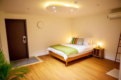um quarto com uma cama e um relógio na parede em Hostel Mihojae Busan em Busan