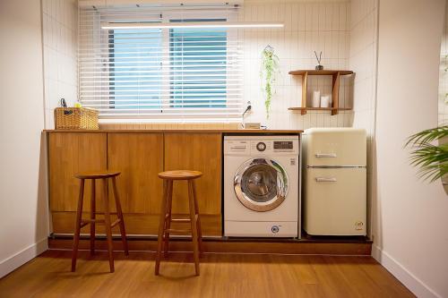 a kitchen with a washing machine and two stools at Hostel Mihojae Busan in Busan