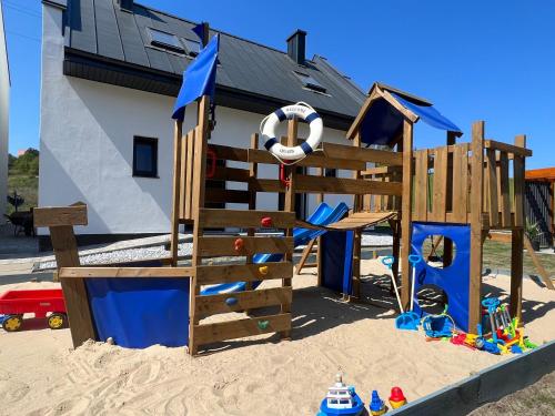 a playground in the sand in front of a house at Morskie Opowieści - domki z klimatem in Władysławowo