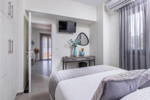 a white bedroom with a bed and a mirror at Luxury Katsoulakis Apartments in Alikianós