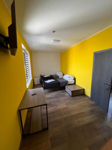a room with yellow walls and a bed and a table at Motel Sun Lit in Ivano-Frankivsʼk