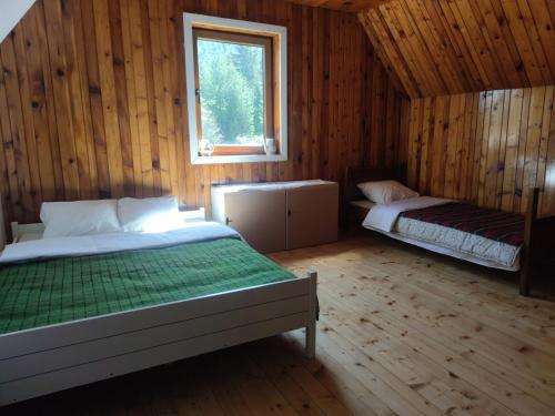 a bedroom with two beds in a wooden cabin at Vukov Konak - Wolf's lodge in Žabljak