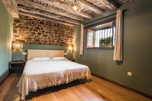 a bedroom with a bed and a brick wall at Mirador De Picos in Aliezo