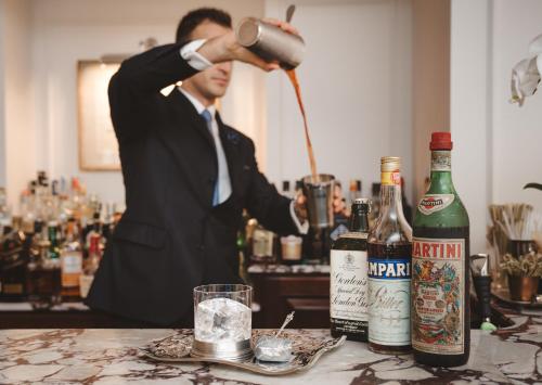 a man in a suit pouring a drink at a bar at Hotel Lungarno - Lungarno Collection in Florence